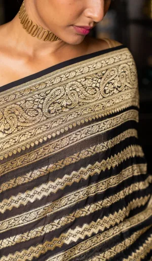 Close-up of a woman draped in a handwoven black and gold Banarasi saree with intricate patterns and a matching choker necklace.
