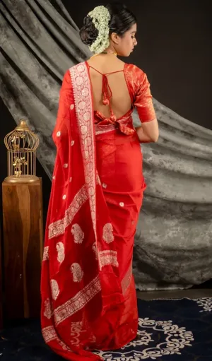 Back view of a model wearing a Handwoven Pure Khadi Georgette Banarasi saree in red, featuring intricate white floral and paisley motifs along the border. The saree is styled with a modern tie-back blouse