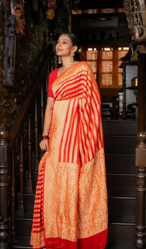 Woman draped in a handwoven orange and red saree with intricate patterns, standing on a staircase.