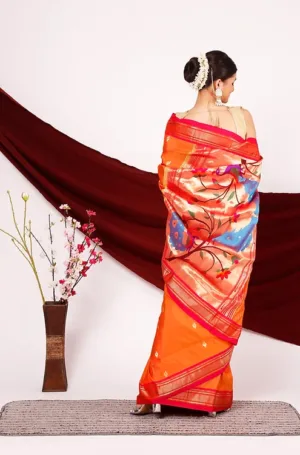 Orange and red handloom pure silk Paithani saree with multicolour handwoven peacock and floral pallu, back view worn by woman