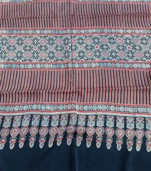Traditional striped cotton fabric with intricate floral and paisley patterns in red, blue, and white, featuring a decorative fringe design in navy blue at the bottom.
