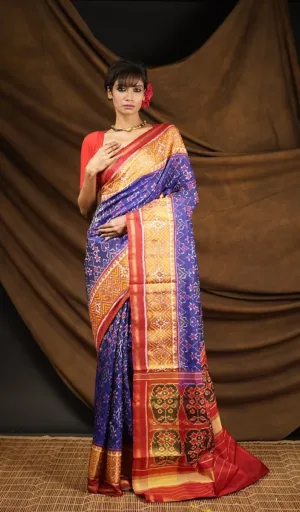 Woman wearing blue mulberry silk handcrafted single ikat Patola saree with gold and red woven border