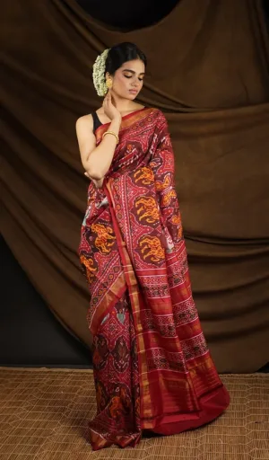 Woman wearing maroon mulberry silk handcrafted single ikat Patola saree with traditional animal motifs and rich woven border