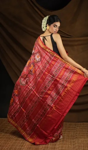 Woman wearing red mulberry silk handcrafted single ikat Patola saree with traditional woven motifs and rich border