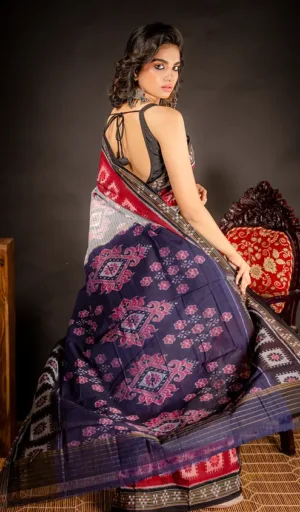 Woman wearing navy blue handloom Odisha ikat cotton saree with red and grey traditional woven motifs