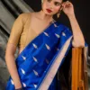 A woman wearing a blue Chanderi saree with gold leaf patterns, paired with a beige blouse and traditional jewelry.