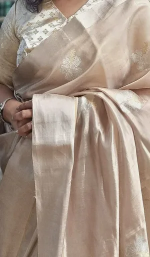 Woman wearing a beige handloom pure silk Chanderi saree with intricate gold embroidery and a matching blouse.